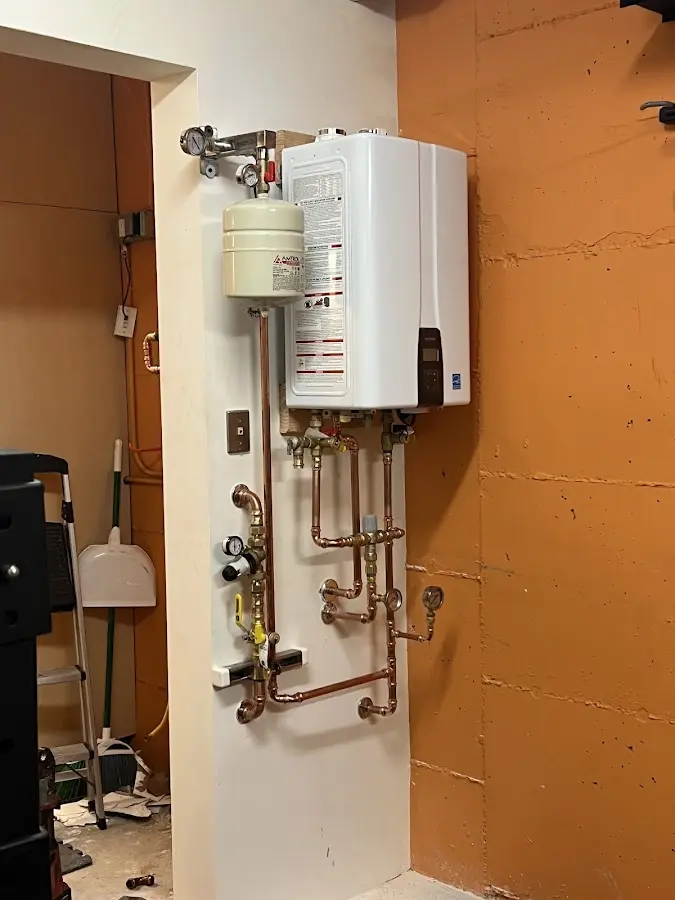 Plumbing technician inspecting water heater connections in New Kingman-Butler